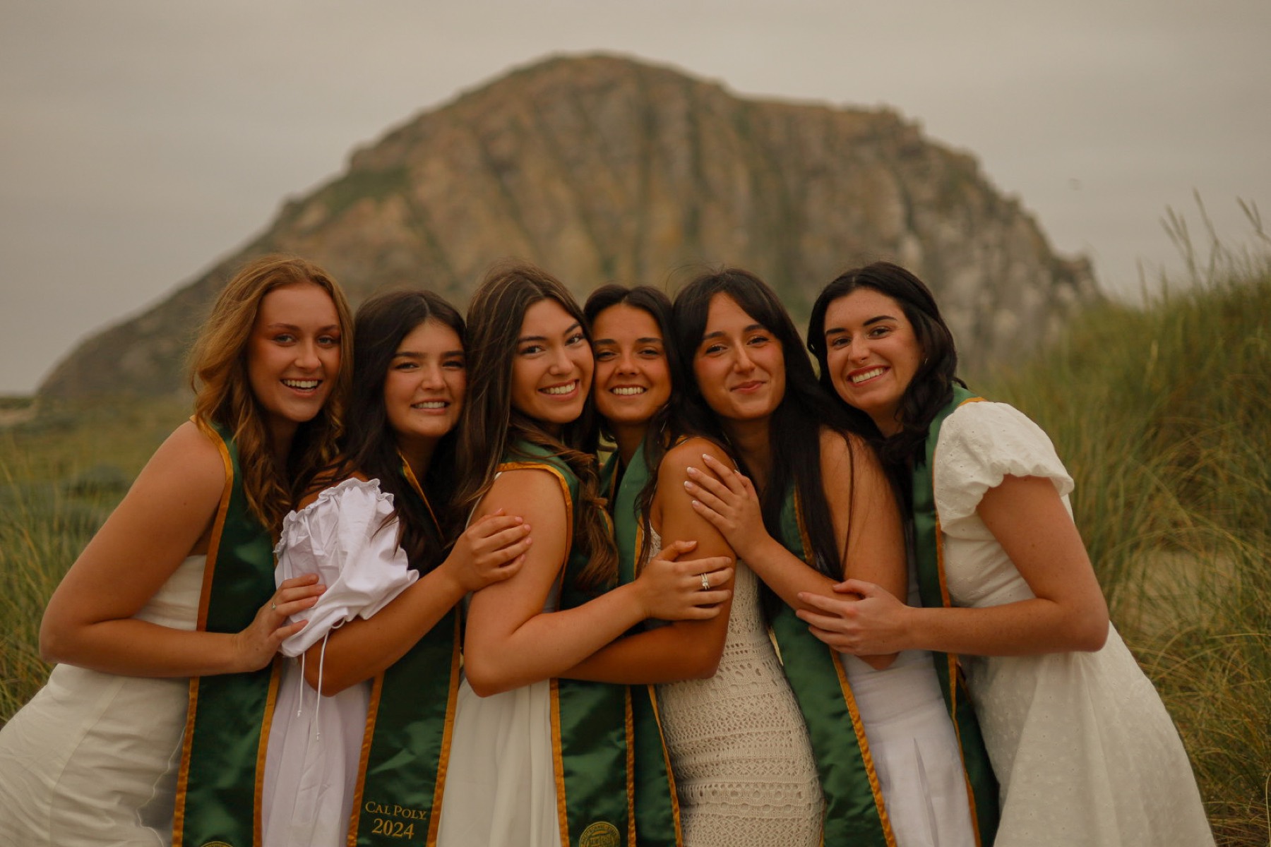 Group of graduates hugging in front of Morro Rock