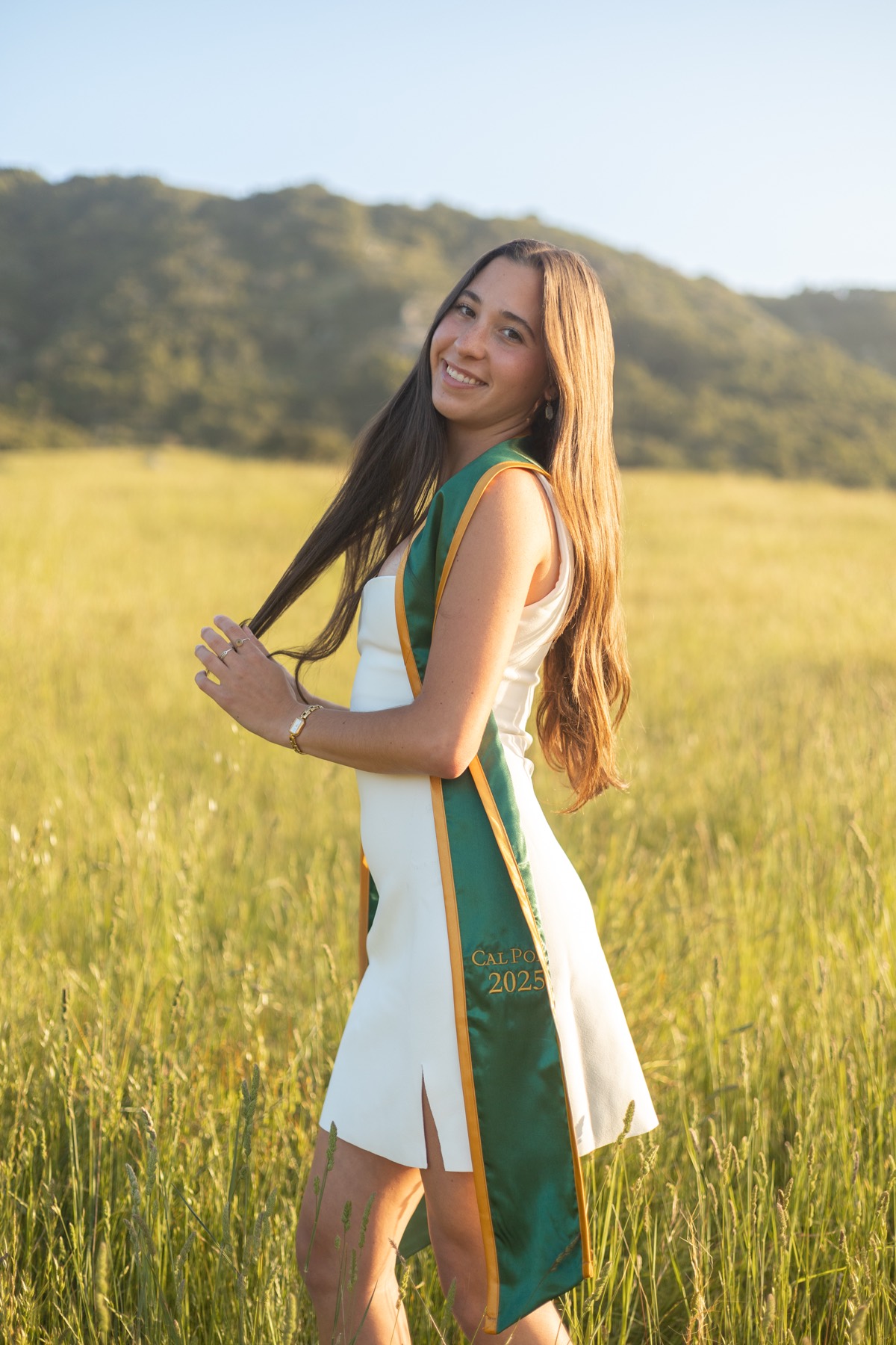 Cal Poly 2025 graduate in a golden field, playing with her hair